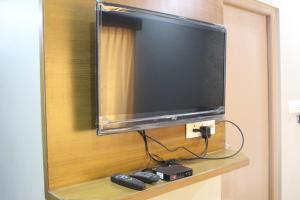 TV de pantalla plana en una pared con mando a distancia en Olivia Inn And Suites, en Bangalore