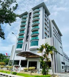 a large white building with palm trees in front of it at Langkawi Seaview Hotel in Kuah