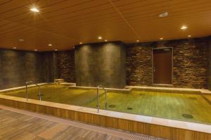 una vasca idromassaggio in una stanza con un muro di pietra di Hot Spring Osaka Hinode Hotel Nipponbashi ad Osaka