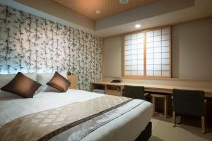 una camera da letto con un letto, una scrivania e una finestra di Hot Spring Osaka Hinode Hotel Nipponbashi ad Osaka