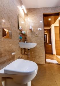 La salle de bains est pourvue de toilettes blanches et d'un lavabo. dans l'établissement Aloka Stay Inn, à Vellore