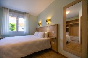 - une chambre avec un grand lit et un grand miroir dans l'établissement Contact HOTEL LES TERRASSES, au Le Verdon-sur-Mer