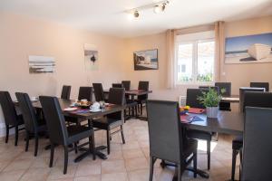 un comedor con mesas y sillas de madera, mesa y sillón en Contact HOTEL LES TERRASSES en Le Verdon-sur-Mer