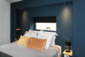 a blue bedroom with a bed with white pillows at Hoeve Altena Cottage in Woudrichem