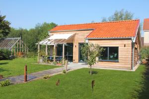 een houten huis met een oranje dak in een tuin bij Hoeve Altena Cottage in Woudrichem