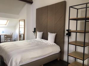 a bedroom with a white bed with a wooden headboard at Brussel House Basilic in Brussels