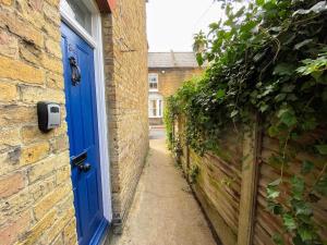an alley with a blue door in a brick building at Spacious Canterbury City Centre Gem House with Parking in Canterbury