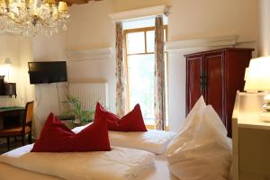 two beds in a hotel room with red pillows at Baderhaus in Bruck an der Mur
