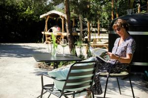 a woman sitting at a table reading a newspaper at B&B Perron 22 in Vierlingsbeek