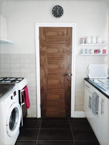 a kitchen with a washer and a wooden door at Richmond Luxury flat Fabulous location in Southend-on-Sea