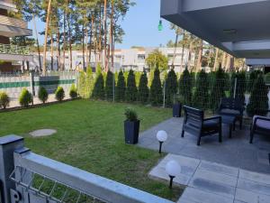 a patio with a lawn with chairs and tables at Apartament Baltica z ogródkiem in Pogorzelica