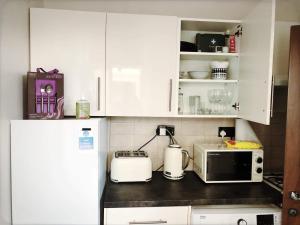 a kitchen with white cabinets and a microwave at Richmond Luxury flat Fabulous location in Southend-on-Sea