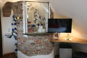 a room with a brick wall with a desk and a television at Baderhaus in Bruck an der Mur