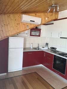 cocina con armarios rojos y nevera blanca en APARTMANI KREŠIĆ 1 HVAR, en Hvar