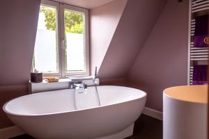 een wit bad in een badkamer met een raam bij B&B Saint-Georges -Located in the city centre of Bruges- in Brugge