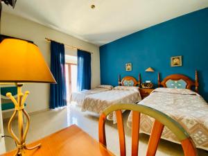 Dormitorio azul con 2 camas y lámpara en Hostal León en Trujillo