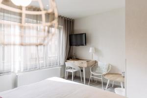 1 dormitorio con 1 cama, escritorio y TV en C-Hotels Helios, en Blankenberge