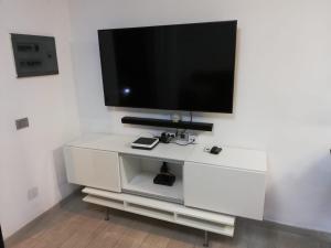 un centro di intrattenimento bianco con TV a schermo piatto a parete di Vistagolf Maspalomas a Maspalomas