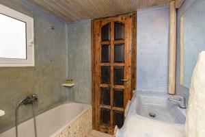 a bathroom with a bath tub and a wooden door at Peristeronas Village in Klouvas