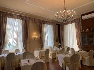 uma sala de jantar com mesas e cadeiras brancas e janelas em Grand Hotel & des Anglais em Sanremo