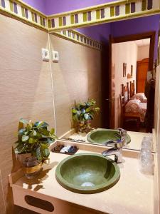 baño con lavabo verde y espejo en Hostal León, en Trujillo
