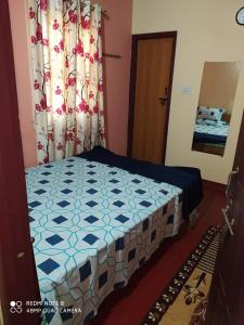 a bedroom with a bed with a blue and white quilt at VANASIRI COTTAGE (Tourist Home) in Dharmastala