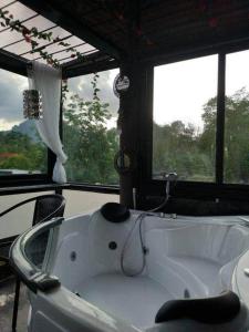 a white bath tub in a room with windows at Keeree Loft Resort in Thong Pha Phum