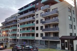 a large apartment building with cars parked in front of it at Apartament Verona in Krynica Zdrój