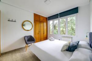 een slaapkamer met een bed, een stoel en een spiegel bij Menditxo Eder Rooms in San Sebastian