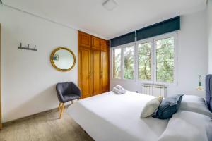 sypialnia z łóżkiem, krzesłem i lustrem w obiekcie Menditxo Eder Rooms w mieście San Sebastián