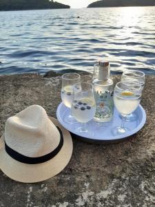 a plate with glasses and a hat next to the water at Apartments Nena in Molunat