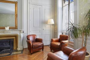 een woonkamer met 2 stoelen en een open haard bij Hôtel Vaubecour in Lyon