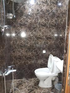 ein Bad mit einem WC und einer gefliesten Wand in der Unterkunft temuriRoom 558-58-78-27 in Poti