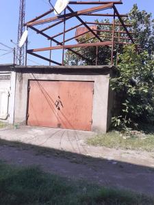 un garage avec une porte rouge et un toit rouillé dans l'établissement temuriRoom 558-58-78-27, à Poti