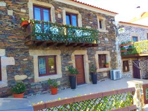 um edifcio de pedra com uma varanda com plantas em Meimoa Guesthouse em Meimoa