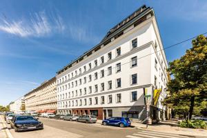 ein großes weißes Gebäude auf einer Straße mit parkenden Autos in der Unterkunft JR City Apartments Vienna in Wien