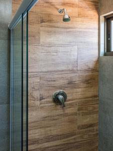 a shower with a wooden door with a shower head at Ilusion Hotel in Natal