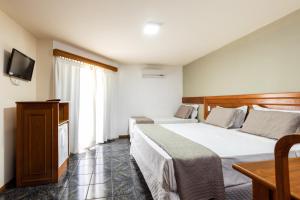 una camera d'albergo con due letti e una televisione di Canzi Cataratas Hotel a Foz do Iguaçu