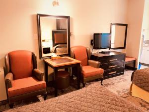 a hotel room with two chairs and a television at Red Carpet Inn & Suites in Calgary