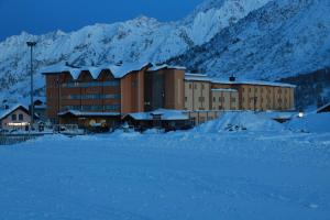 a large building with snow covered mountains in the background at Grand Hotel Miramonti in Passo del Tonale