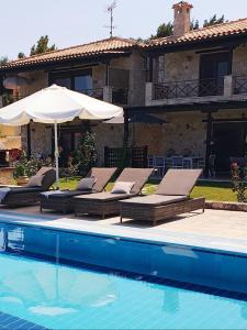una piscina con sillas, una sombrilla y una casa en Villa Sandra, en Kriopigi