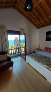 um quarto com uma cama e vista para o oceano em Sara Village em São Roque do Pico