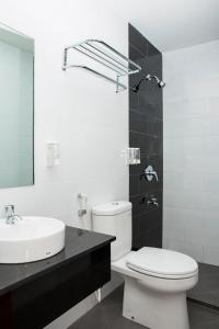 a bathroom with a white toilet and a sink at DeMira Hotel in Surabaya