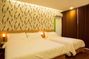 Dos camas en una habitación de hotel con sábanas blancas. en DeMira Hotel, en Surabaya