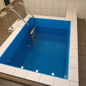 bañera azul en una habitación con azulejos blancos en Оселя Драгобрат en Dragobrat