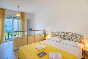 a bedroom with a large bed with a yellow blanket at Hotel Casa Piantoni in Limone sul Garda