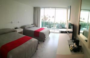 アカプルコにあるWe Hotel Acapulcoのベッド2台と大きな窓が備わるホテルルームです。