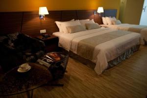 una camera d'albergo con due letti e un divano di Pine Tree Hotel a Batu Pahat