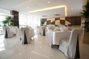 Pine Tree Hotel في باتو باهات: غرفة طعام مع طاولات بيضاء وكراسي بيضاء