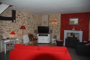 een woonkamer met een rode bank en een tv bij Ty Kergate in Sulniac